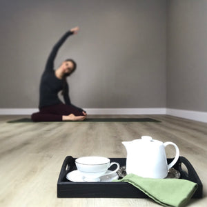 White tea pot and cup on a silver and black tray. Owner posed in a Pilates mermaid.